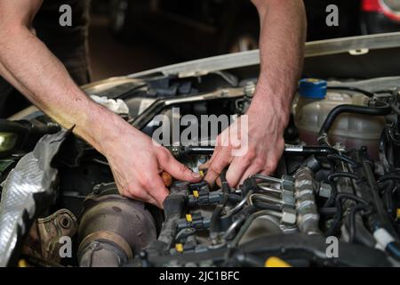 Close up of car mechanic hands removing fuel injectors. Stock Photo
