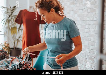Woman working at home in tailoring creative studio diy hobby. Adult female people have leisure time indoor. People work in apartment. Lady take size o Stock Photo