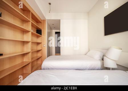A bright bedroom with two twin beds, a desk and chair, wall art