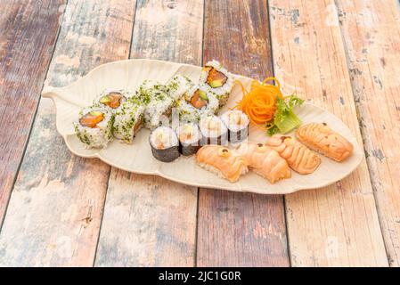 Mixed sushi tray with rice maki with Norwegian salmon, nigiris with salmon flambé and uramaki with salmon and avocado and chopped parsley Stock Photo