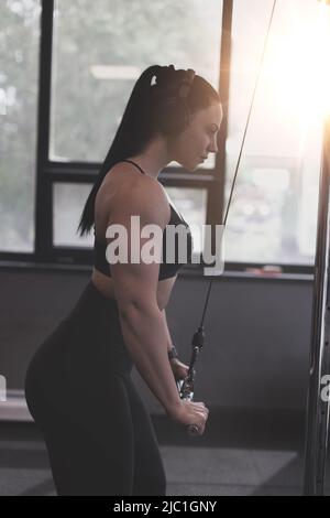 Muscular bodybuilder woman triceps workout in gym and sunlight Stock Photo