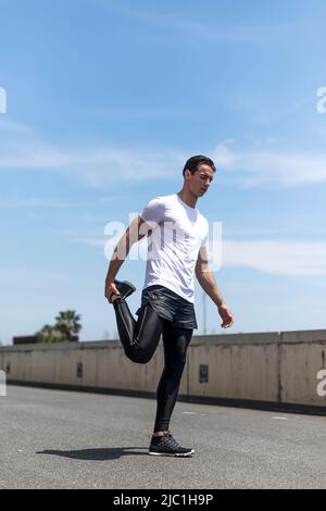 Sport man is stretching leg muscle before to exercise or running in the central park Stock Photo