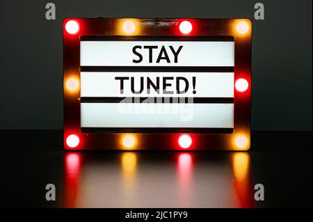 Lightbox with red and orange lights in dark room with words - stay tuned! Stock Photo