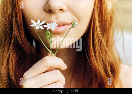 Woman holding a spring flower in her hand in sunlight, conservation and ecology Stock Photo