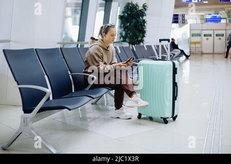 young woman using her smartphone at the airport . Stock Photo