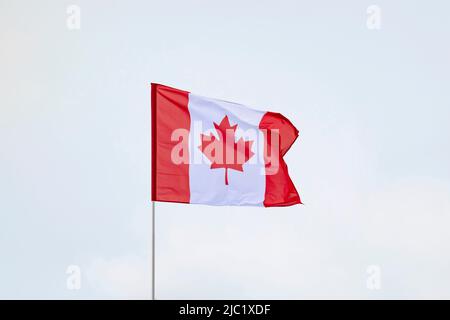Flag of Canada developing against a clear blue sky Stock Photo