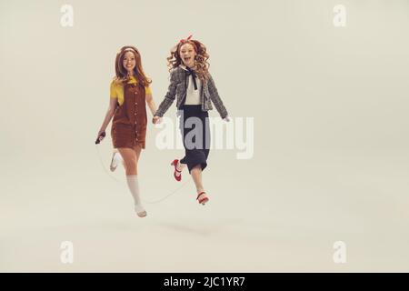 Pretty young girls in retro 70s, 80s, 90s fashion style, outfits isolated  over white studio background. Concept of eras comparison, beauty, vintage  Stock Photo - Alamy