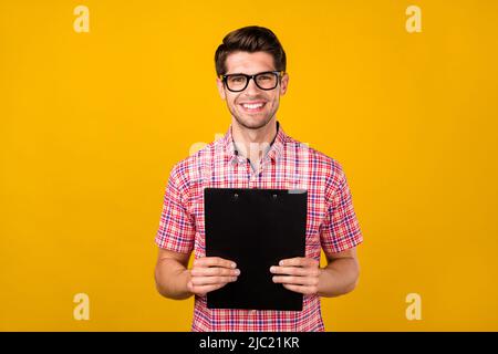 Photo of young business man happy positive smile hold clipboard interview hr isolated over yellow color background Stock Photo