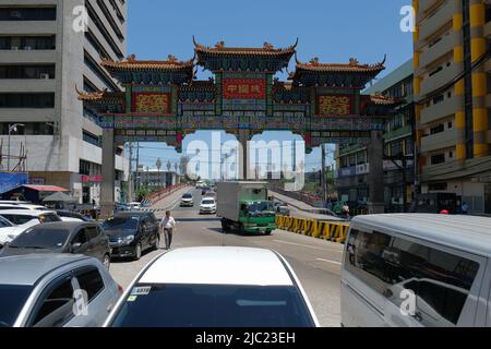 Manila, Philippines: cars passing from Jones Bridge through the world's largest Chinatown Arch (2015) in the world's oldest Chinatown, Binondo (1594). Stock Photo