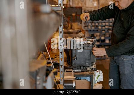 Close up of repairman with screwdriver fixing coffee machine at table indoors Stock Photo