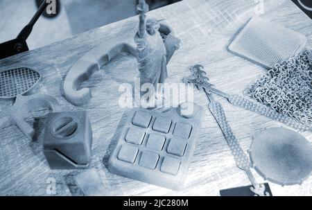 Many different models printed on 3D printer. Gray and black objects printed on 3D printer made of plastic close-up. Lots of 3D printed models. Prototypes of various shapes made by 3d printer on table. Stock Photo