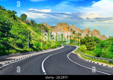 Picturesque mountain road winds its way through the Crimean mountains near the Black Sea coast against a blue sky on a sunny day. Crimea, Ukraine Stock Photo