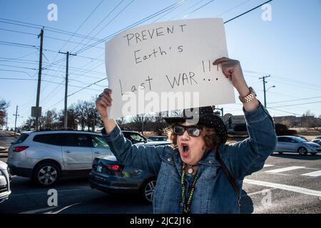 01-04-2020 Older woman in cowboy hat and much jewelry chants as she holds up sign Prevent Earths Last War Stock Photo