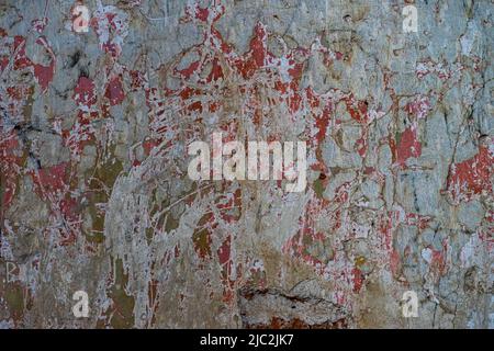 Remains of red paint on the gray plaster of the ruined building. Stock Photo