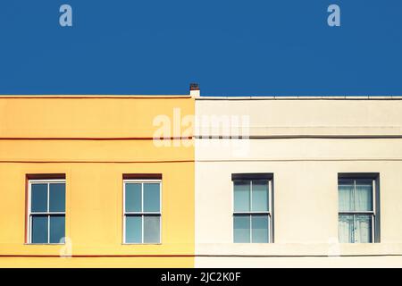 Yellow house, white house and blue sky. Minimalism style with space for text. geometric window and rook detail Stock Photo