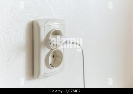 Close-up of a smartphone charger connected to a euro socket. Stock Photo
