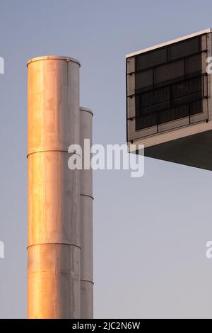 Helsinki / Finland - JUNE 6, 2022: Closeup of two metallic smoke stacks and a air conditioning exhaust grille during the sunset Stock Photo