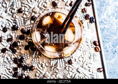 Close-up of an iced coffee drink on metal tray with roasted coffee beans Stock Photo