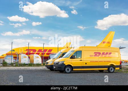 Schkeuditz, Germany - 29th May, 2022 - Many courier van against cargo planes parked on Leipzig Halle airport terminal apron for loading distribution Stock Photo