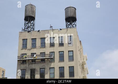 Renovation work being done on older apartment building with old iconic water towers on top in lower Manhattan. Stock Photo