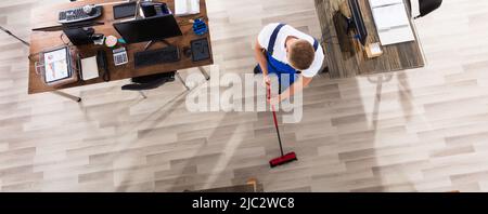 Elevated View Of Male Janitor Cleaning Floor With Broom At Workplace Stock Photo