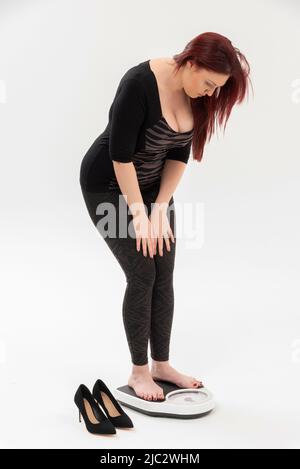 Wiltshire, England, UK. 2022. Woman using a set of bathroom scales to check her weight. Stock Photo