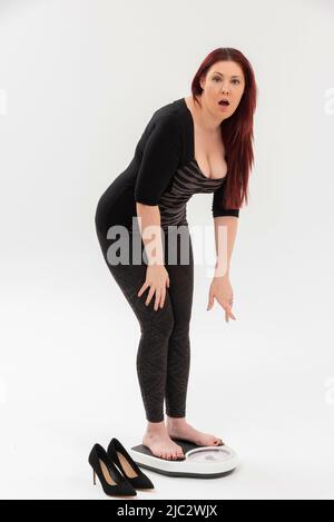 Wiltshire, England, UK. 2022. A surprised woman using a set of bathroom scales to check her weight. Stock Photo