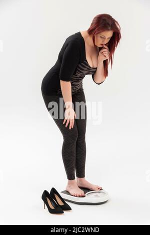 Wiltshire, England, UK. 2022. Woman using a set of bathroom scales to check her weight. Stock Photo