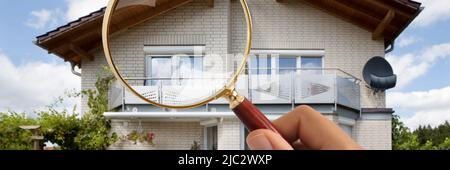 Close-up Of Person's Hand Holding Magnifying Glass Over Luxury House Outdoors Stock Photo