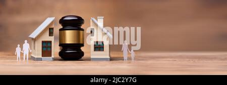 Close-up Of Gavel Between Split Family Figures And House Model On Wooden Desk Stock Photo