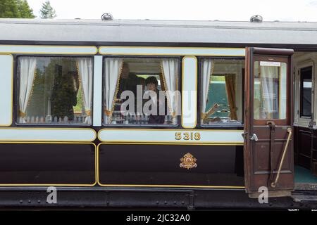 Woman by window of London North Western Railway steam train at Bolton Abbey Steam Railway Stock Photo