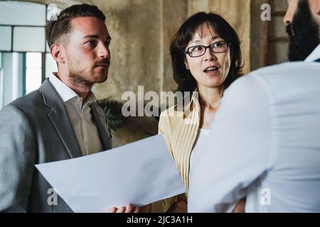 Multiethnic business people working inside bank office - Focus on Asian senior woman face Stock Photo