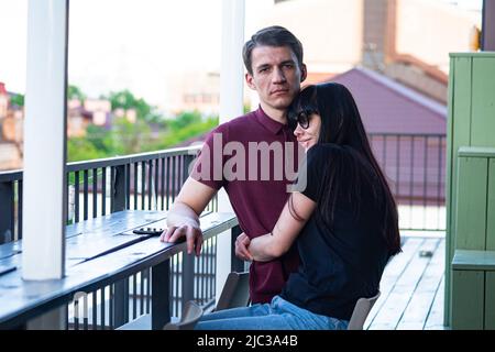 Young pretty woman hugs her man on the roof top in Kiev on Podil (lower city) district, couple enjoys together early June after  turbulent spring 2022 Stock Photo