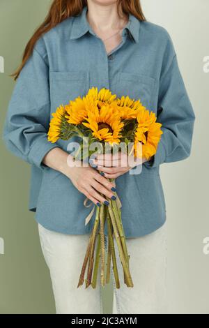 Ukrainian woman with a bunch of sunflowers on white wall background Stock Photo