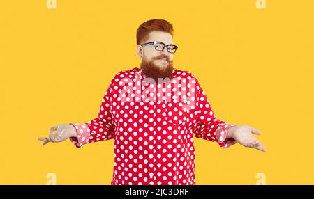 Funny stylish bearded fat man who knows nothing or doubts and therefore shrugs on orange background Stock Photo