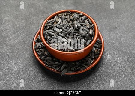 Bowl and plate of black sunflower seeds on dark background Stock Photo