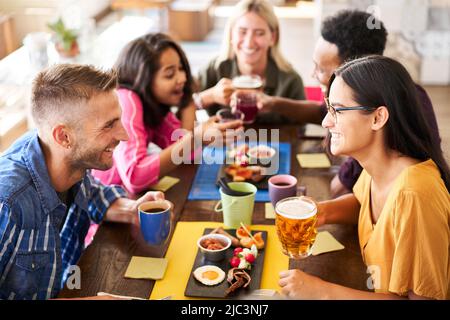 People having fun at bar. Friends taking lunch time drinking beer and eating cakes. Lifestyle and community concept with happy men and women at cafe Stock Photo