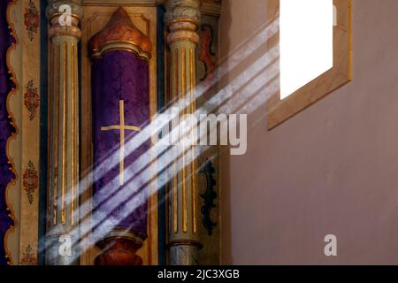 Religious symbol with fabric in purple color with design of the cross receiving sun rays from window light Stock Photo
