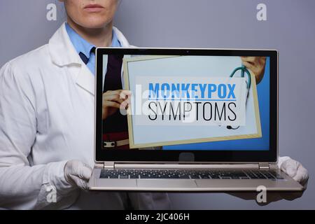 Closeup on modern medical doctor woman in white medical robe showing laptop with monkeypox symptoms screen isolated on grey background. Stock Photo