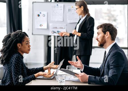 Negotiations of business partners. Successful smart colleagues, an african american woman and a caucasian man, are sitting at a table the office, discussing a new project, a financial business plan Stock Photo