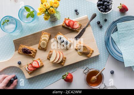 Breakfast crackers with various toppings of fresh fruit and cream cheese spread. Stock Photo