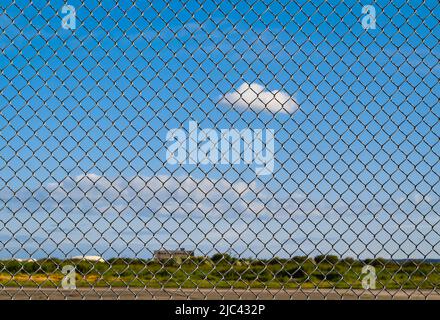Fence with metal grid in perspective. Metal fence Part of a metal grid fence in blue sky at the background. Street view, depth of field, nobody Stock Photo