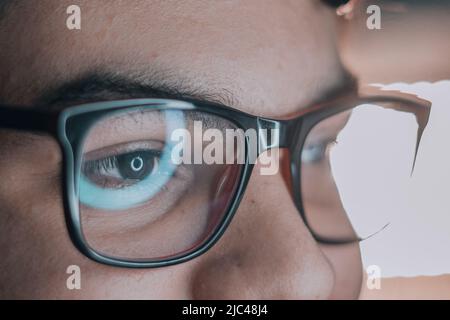 Reflection of a computer screen on a young man's lens Stock Photo
