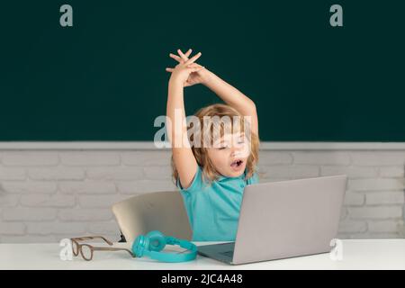 Tired sleepy child using gadgets to study. Computer hard education for kids. Stock Photo