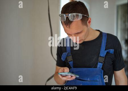Handyman using mobile phone in demolish apartment Stock Photo
