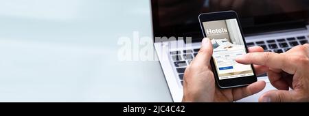 Close-up Of A Man's Hand Booking Hotel Using Smartphone Stock Photo