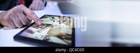 Close-up Of A Businessman Looking At CCTV Camera Footage On Digital Tablet Stock Photo