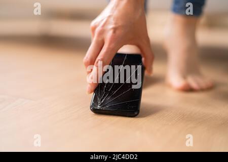 Woman's Hand Picking Up Mobile Phone With Broken Screen Stock Photo