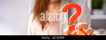 Close-up Of A Businessperson's Hand Holding Red Question Mark Sign Stock Photo