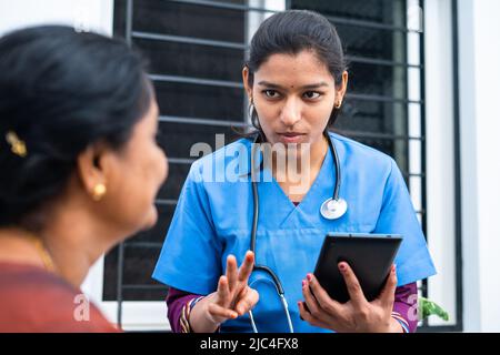 Doctor or nurse advising middle aged woman by seeing report from digital tablet at nursing home - conept of technology, healthcare and medical service Stock Photo